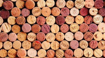 Closeup of a wall of used wine corks. A random selection of use wine corks, some with vintage years. Horizontal format that fills the frame.